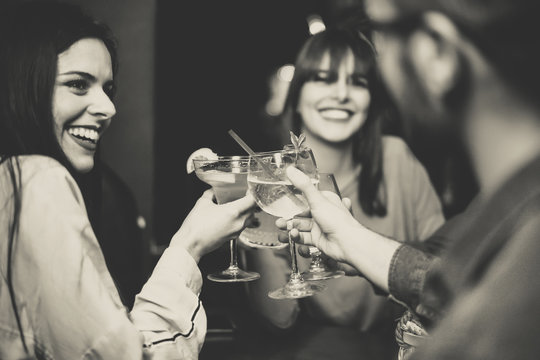 Happy young friends toasting and cheering cocktails at disco bar