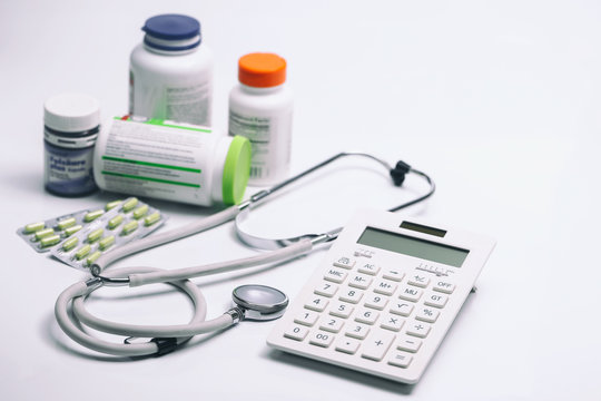 calculator, stethoscope and medicine bottles on white background
