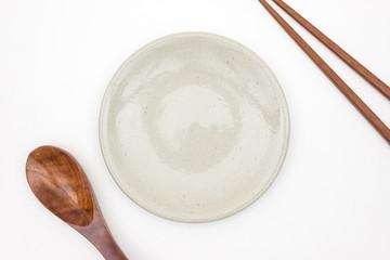 Traditional Japanese wooden chopstick with wooden spoon and white ceramic plate