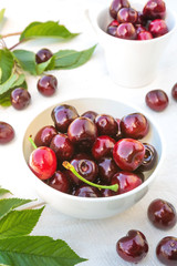 Berries of fresh cherry with cherry green leaves on an old white wooden background
