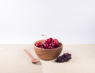 Cherries in  wooden bowl and  wooden spoon ,dark grapes ,flower