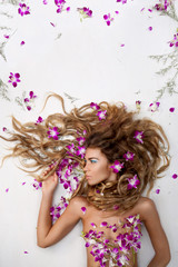 Naklejka na ściany i meble Beautiful adult girl with orchid petals on white background