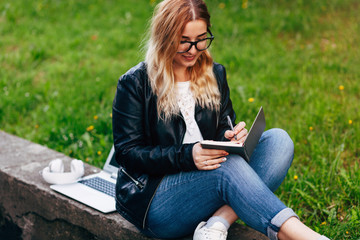 Beautiful Young Woman Writing Her Notebook Outside in City Park