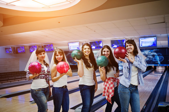 Group of six girls wit bowling balls at hen party on bowling club.