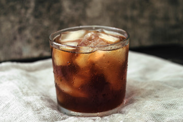 full glass of whiskey with ice on a gray background