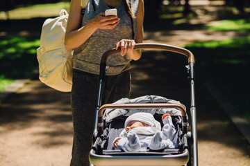Family, parenthood, technology and people concept - young stylish sporty mother with backpack...
