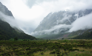 mountain sides engulfed in cloud with green landscape