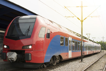 Fototapeta premium Modern high-speed train on a clear day with motion blur. Beautiful railway station with modern red commuter train.