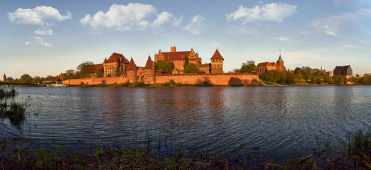 Fototapeta na wymiar Malbork Castle in Poland, medieval fortress of Teutonic Knights Order, view across Nogat River, UNESCO World Heritage Site - panorama 