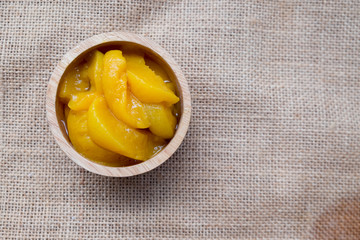 Peeled and sliced peaches in wooden bowl