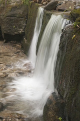 Beautiful waterfalls on golden rocks surrounded by moss on boulders.