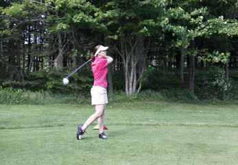 young woman takes a golf swing 