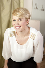 Young smiling blonde woman with short hair in silk blouse.