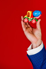 toy in hand of man on red background, car insurance