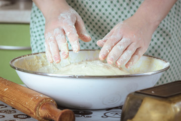 female hands in flour kneading dough in white bowl