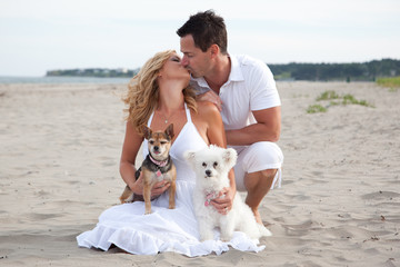  A kissing couple with their pet dogs on the beach