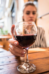 A glass of red wine in a woman's hand. Restaruant summer atmosphere.