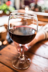 A glass of red wine in a woman's hand. Restaruant summer atmosphere.
