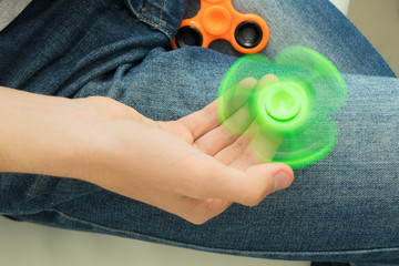trendy fidget spinner - person holding spinning green fidget spinner in hand, close up view
