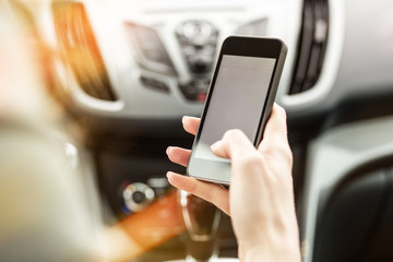 Driver using smart phone in the car.Phone and hands are in focus.