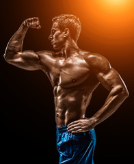 Fototapeta premium Muscular and fit young bodybuilder fitness male model posing ove
