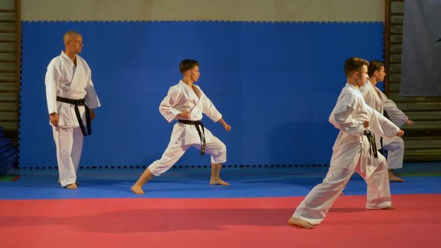 Teenagers martial arts practitioners performing kata at the dojo with sensei karate teacher