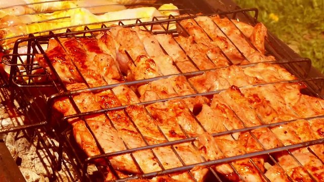 Rotate the grill with chicken. The camera slides along the grill with chicken and meat. Smoke rises from the coal through the meat