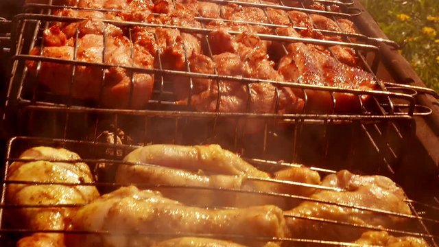 The camera slides along the grill with chicken and meat. Delicious meat steak cooking on the grill. Closeup. Smoke rises from the coal through the meat