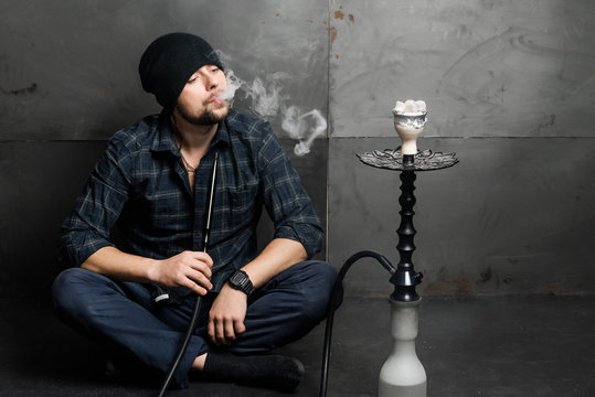 Young handsome bearded man smoking hookah