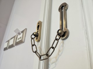 Door locked by door chain for safety room in hotel, closeup.