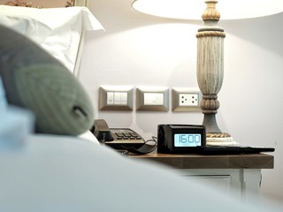 Hotel room alarm clock on beside table. Concept for travel or business.