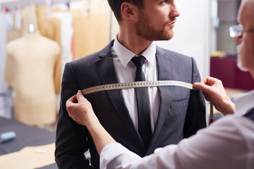Portrait of tailor taking measurements of customer during model fitting - Powered by Adobe
