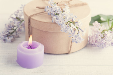 Fototapeta na wymiar Lit purple candle and lilac flowers