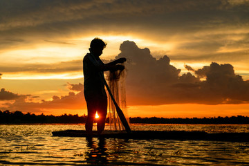 Silhouette fisherman trowing the nets on during sunset,during sunrise,Thailand