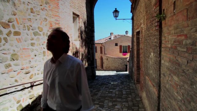 attractive man walking in ancient alley of Italian village