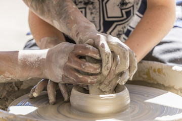 student learning how to make pottery on a wheel 
