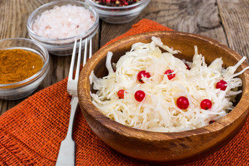 Salted cabbage on plate on the background of wooden table