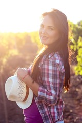 The young beautiful woman walks in the vineyards. Portrait of a beautiful young woman with a hat in...