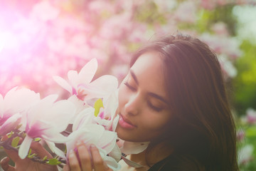 Naklejka premium Happy girl with adorable smile smiling at magnolia tree