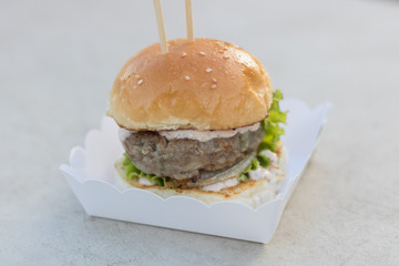 fresh beef burger and mayonnaise sauce and sesame bun serverd on paper box at outdoor.Fast food, street food.