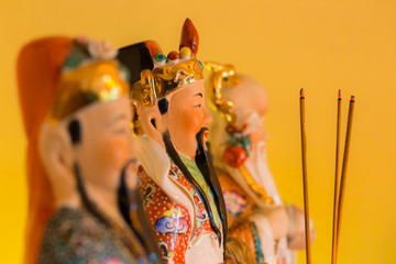 drei Räucherstäbchen stehen vor den chinesischen Hausgöttern Lu, Fu und Shou