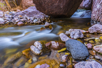 Obraz premium small stream flowing around big boulders in a canyon 