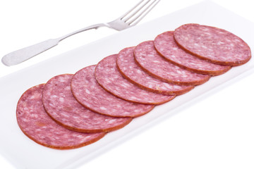 Slices of salami on white plate