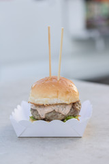 fresh beef burger and mayonnaise sauce and sesame bun serverd on paper box at outdoor.Fast food, street food.