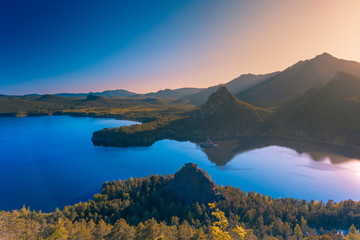 Beautiful sunset over mountain lake blue surface.