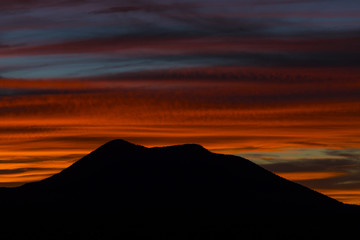 close up of a mountain with a colorful sunset behind it