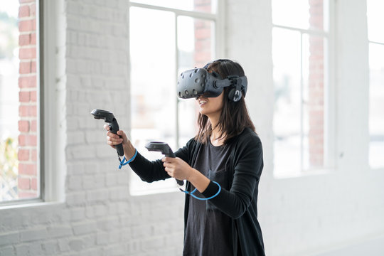 An asian woman wearing a virtual reality headset.
