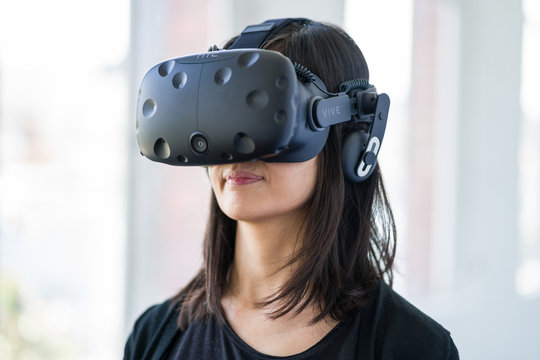 An asian woman wearing a virtual reality headset.