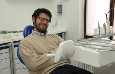 man sitting in dentist chair in dental surgery