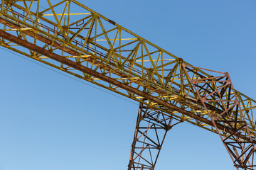 Rusty gantry crane on the background of blue sky.